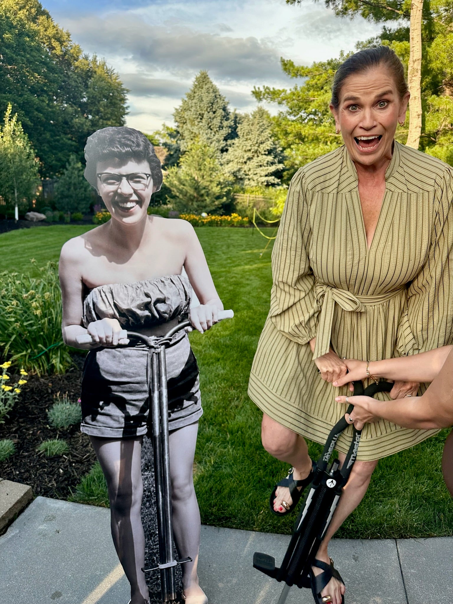 Life-size photo cutout standing outdoors in a back yard beside a laughing guest